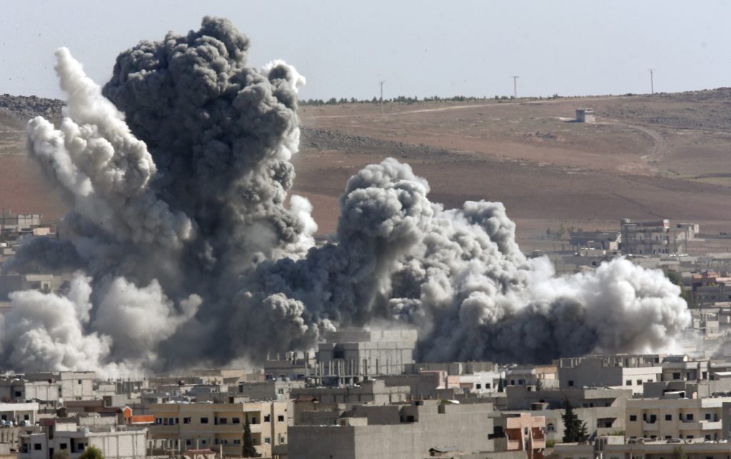 Thick smoke from an airstrike by the US-led coalition rises in Kobani, Syria, as seen from a hilltop on the outskirts of Suruc, at the Turkey-Syria border, Wednesday, Oct. 22, 2014. Kobani, also known as Ayn Arab, and its surrounding areas, has been under assault by extremists of the Islamic State group since mid-September and is being defended by Kurdish fighters. (AP Photo/Lefteris Pitarakis)